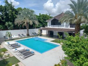 une image d'une piscine avec des chaises et une maison dans l'établissement Au Paradis de Jeanne, à Ngaparou