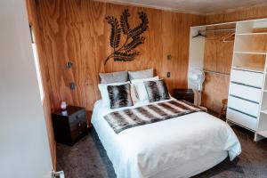 a bedroom with a white bed with a wooden wall at Unwind in Paradise Valley Trout at your door in Rotorua