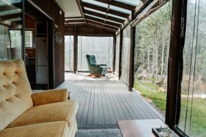 ein Wohnzimmer mit einem Sofa und einem Stuhl auf einer Veranda in der Unterkunft Unwind in Paradise Valley Trout at your door in Rotorua