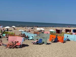 a group of people on a beach with chairs and umbrellas at ZeeBedStay in Noordwijk aan Zee