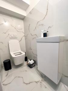 a white bathroom with a toilet and marble walls at Holiday house DOMa Nová Lesná in Nová Lesná