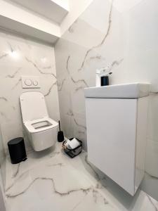 a white bathroom with a toilet and marble walls at Holiday house DOMa Nová Lesná in Nová Lesná +29 photos