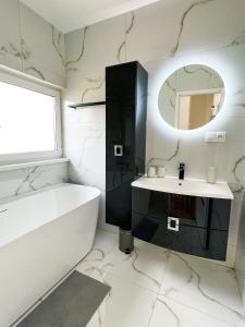a bathroom with a tub and a sink and a mirror at Holiday house DOMa Nová Lesná in Nová Lesná
