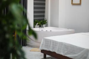 a white bathroom with a tub and a plant at Green Line Long Bien - Serviced Apartment - Ngoc Thuy - Hanoi in Hanoi