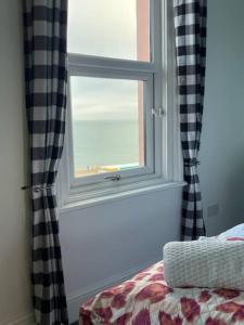1 dormitorio con ventana y vistas al océano en "The Parlour" Seafront Apartment, en Eastbourne