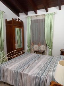 1 dormitorio con 1 cama con cortinas verdes y espejo en Casa vacanze Monterosso, en Ravanusa