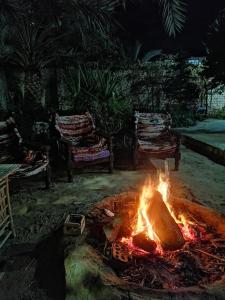 a fire in the middle of a yard with two chairs at Green House in Al Manshīyah