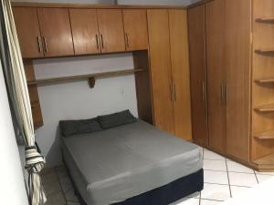 um pequeno quarto com uma cama e armários de madeira em Nova ADM - Hostel Pérolas de Peruíbe em Peruíbe