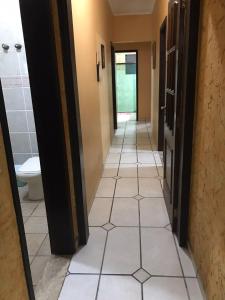 a hallway of a bathroom with a toilet and tile floor at Nova ADM - Hostel Pérolas de Peruíbe in Peruíbe