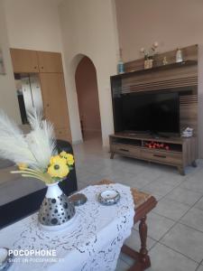 una sala de estar con un jarrón con flores sobre una mesa en Κεντρικό, ανετο και ευρύχωρο διαμέρισμα en Kamena Vourla
