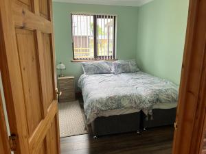 a small bedroom with a bed and a window at Cheerful 3-bedroom cabin with hot tub in Kings Lynn