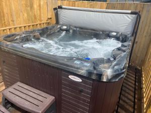 a hot tub with a bench in front of it at Cheerful 3-bedroom cabin with hot tub in Kings Lynn