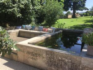 un estanque koi en un jardín con césped en La Grande Maison, en Montmeyran