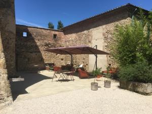 eine Terrasse mit einem Tisch und einem Sonnenschirm in der Unterkunft La Grande Maison in Montmeyran