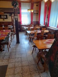a restaurant with wooden tables and chairs and red curtains at Penzion Krušnohorka in Tatrovice