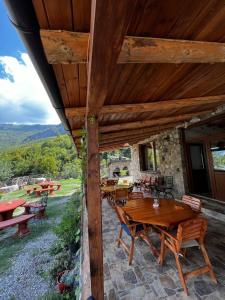 a patio with wooden tables and chairs on a house at Guest House Aprripe Guri in Fierzë