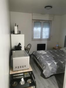 a bedroom with a bed and a microwave on a table at Appartement Studio Gare SNCF in Beauvais