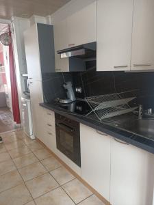 a kitchen with white cabinets and a black counter top at Ideal Sejour - Le Mont-Dore in Le Mont-Dore