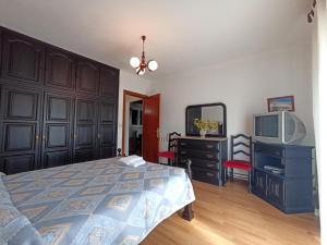 Schlafzimmer mit einem Bett, einem TV und einer Kommode in der Unterkunft Casa Machado in Vila Real