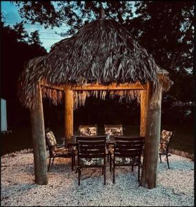 a pavilion with chairs and a table with a straw roof at Private Oasis at Palm Casita in St. Petersburg