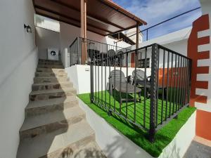 uma casa com um portão com duas cadeiras e relva em Vv Puerto del Trigo - Stella em Alojera