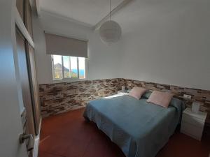 a bedroom with a bed and a brick wall at Vv Puerto del Trigo - Stella in Alojera