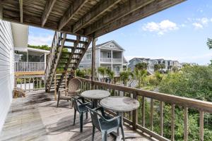 a balcony with tables and chairs and a view of the ocean at Sunflower in Holden Beach