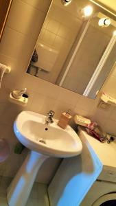 La salle de bains est pourvue d'un lavabo blanc et d'un miroir. dans l'établissement FratoscanoHouse DOLOMITI Villaggio Veronza val di Fiemme max 4pax by fdnfashion, à Carano