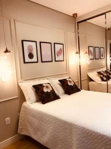 1 dormitorio con 1 cama con 2 almohadas y espejo en Casa Luxo com piscina a 500 metros da praia en Florianópolis