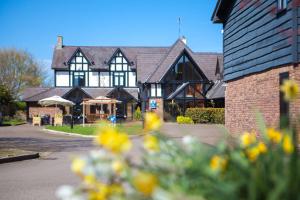 a large black and white building with yellow flowers in the foreground at Best Western Gables Hotel in Falfield