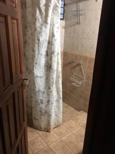 a shower with a white shower curtain in a bathroom at Hermosa cabaña con vista a la montaña in Tunuyán