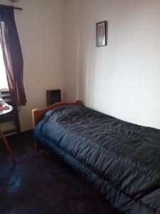 - une chambre avec un lit et une couverture noire dans l'établissement Coralca, à Martínez