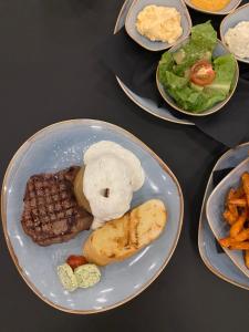 einen Teller mit Fleisch, Gemüse und Pommes frites in der Unterkunft OLÉ Hotel in Hamburg
