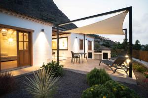 - une terrasse avec une table et un grand parasol dans l'établissement BASÂLTO Casas Rurales, à Hermigua