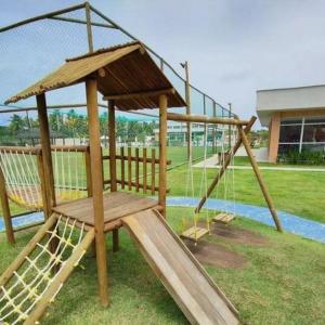 a wooden playground with a slide and a swing at Flat Muro Alto Porto de Galinhas in Porto De Galinhas
