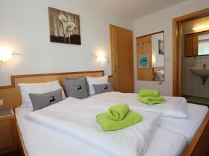 1 dormitorio con 2 camas y toallas verdes. en Apart Altavista, en Kappl