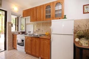 a kitchen with wooden cabinets and a white refrigerator at Apartments with a parking space Zavala, Hvar - 8773 in Zavala
