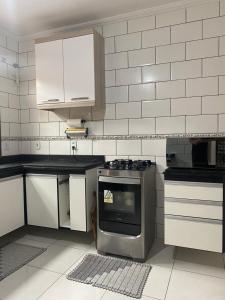 uma cozinha com um fogão e armários brancos em Casa com piscina cabo frio em Cabo Frio