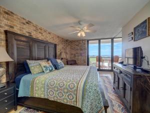 a bedroom with a bed with a television and a brick wall at Costa Crinks at Aransas Princess in Port Aransas