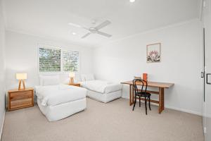 a white living room with a table and a couch at Lawson Beachfront in Byron Bay