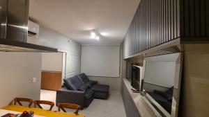 a living room with a couch and a television at Condomínio Barretos Thermas Park - Flat Parque do Peão in Barretos