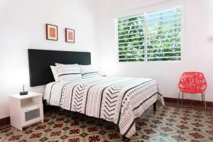 1 dormitorio con cama, ventana y silla roja en Casa Isabel B&B, en San Juan