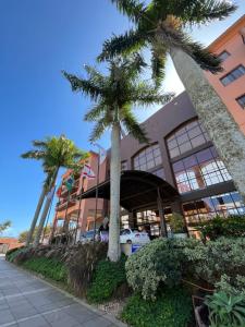 a building with palm trees in front of it at Jurerê Beach Village - Suíte in Florianópolis