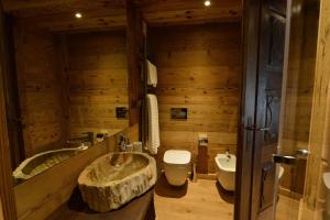 La salle de bains est pourvue d'un lavabo, de toilettes et d'une baignoire. dans l'établissement La Maison de Dolphe Chalet de Charme & Art gallery, à Brusson