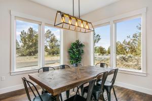 a dining room with a table and chairs and windows at Juniper Ranch House at Brasada Ranch Resort in Alfalfa