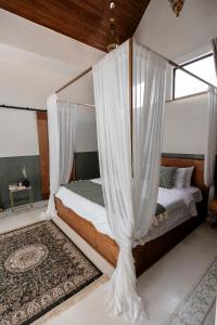 Schlafzimmer mit einem Bett mit weißen Vorhängen in der Unterkunft Villa Medina Canggu in Canggu