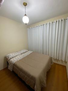 um quarto com uma cama e uma cortina branca em Apto com garagem no centro de Nova Friburgo em Nova Friburgo