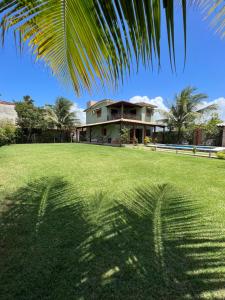 a palm tree shadow on the grass in front of a house at Casa em Peroba/Maragogi in Maragogi