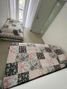 two beds in a room with a quilt at Apartamento pé na areia in Itanhaém