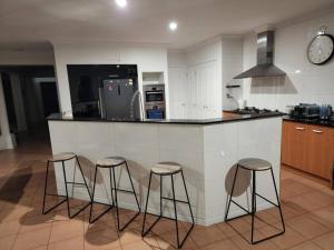 a kitchen with three bar stools at a counter at Centelle Park Farm Stay in Kilmore East